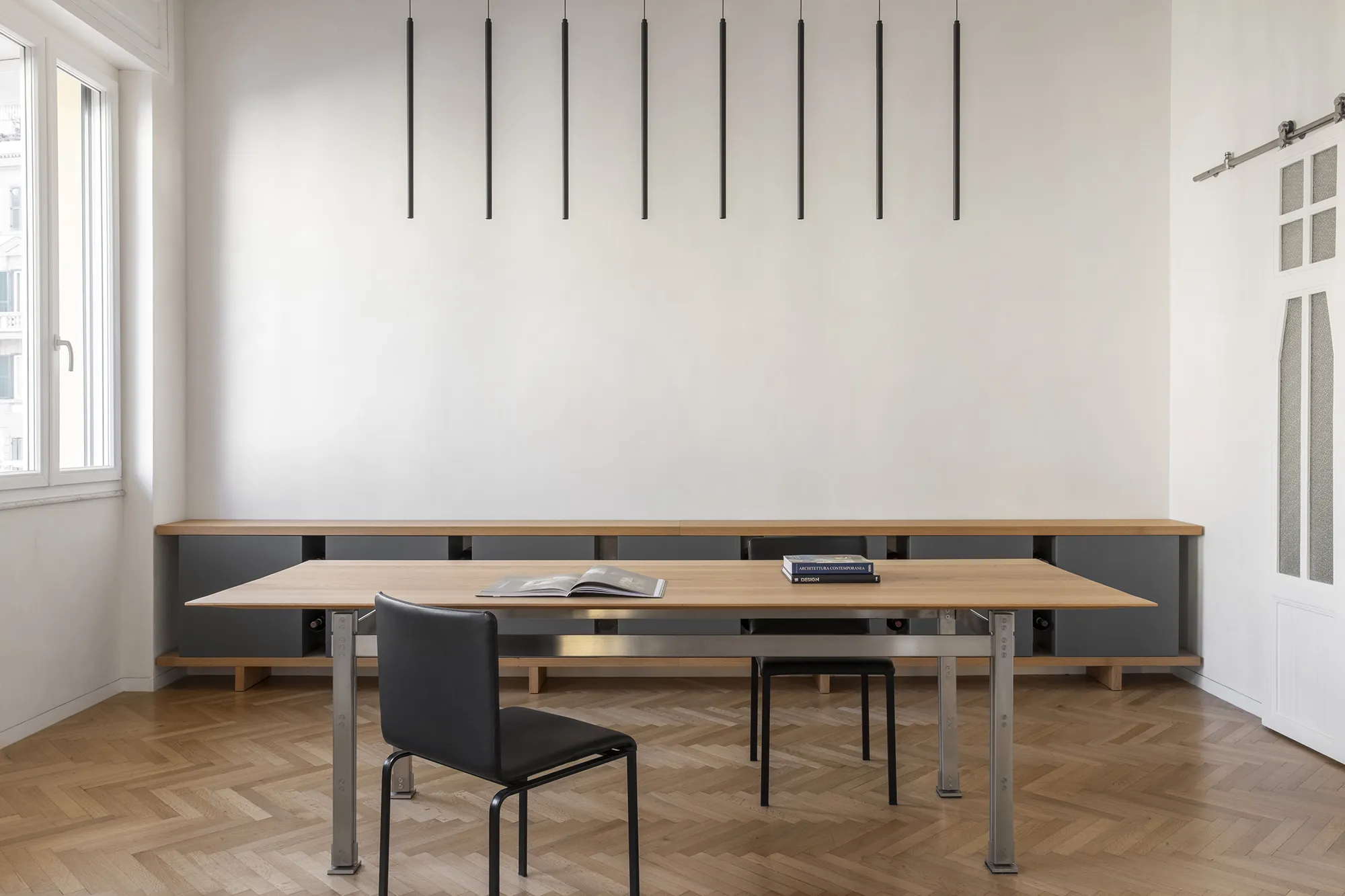 Tavolo da pranzo minimalista in legno di rovere e acciaio in un interno moderno con parquet a spina di pesce