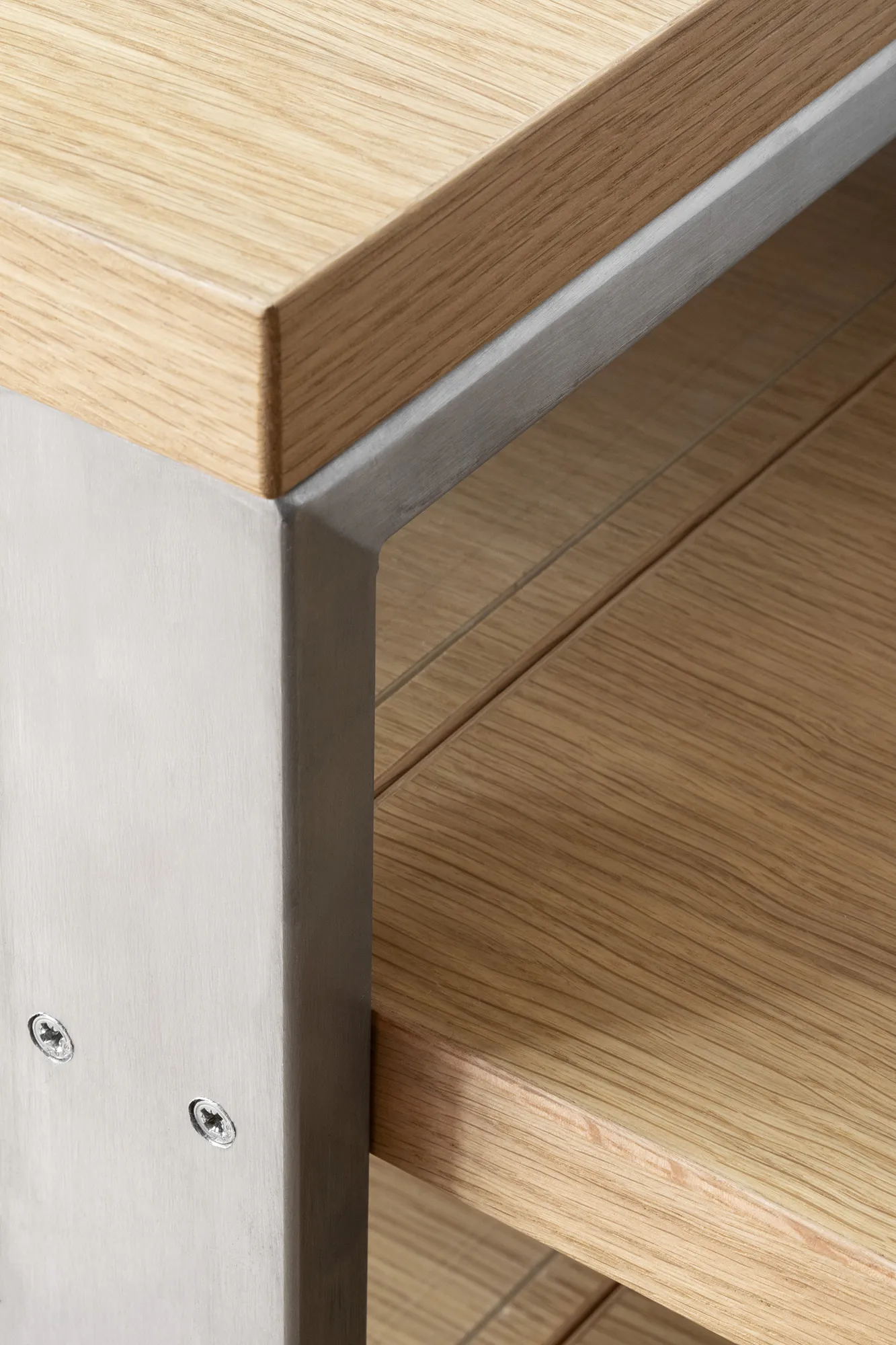 Primo piano del piano in rovere massello e montante in acciaio inox satinato con viti a vista.